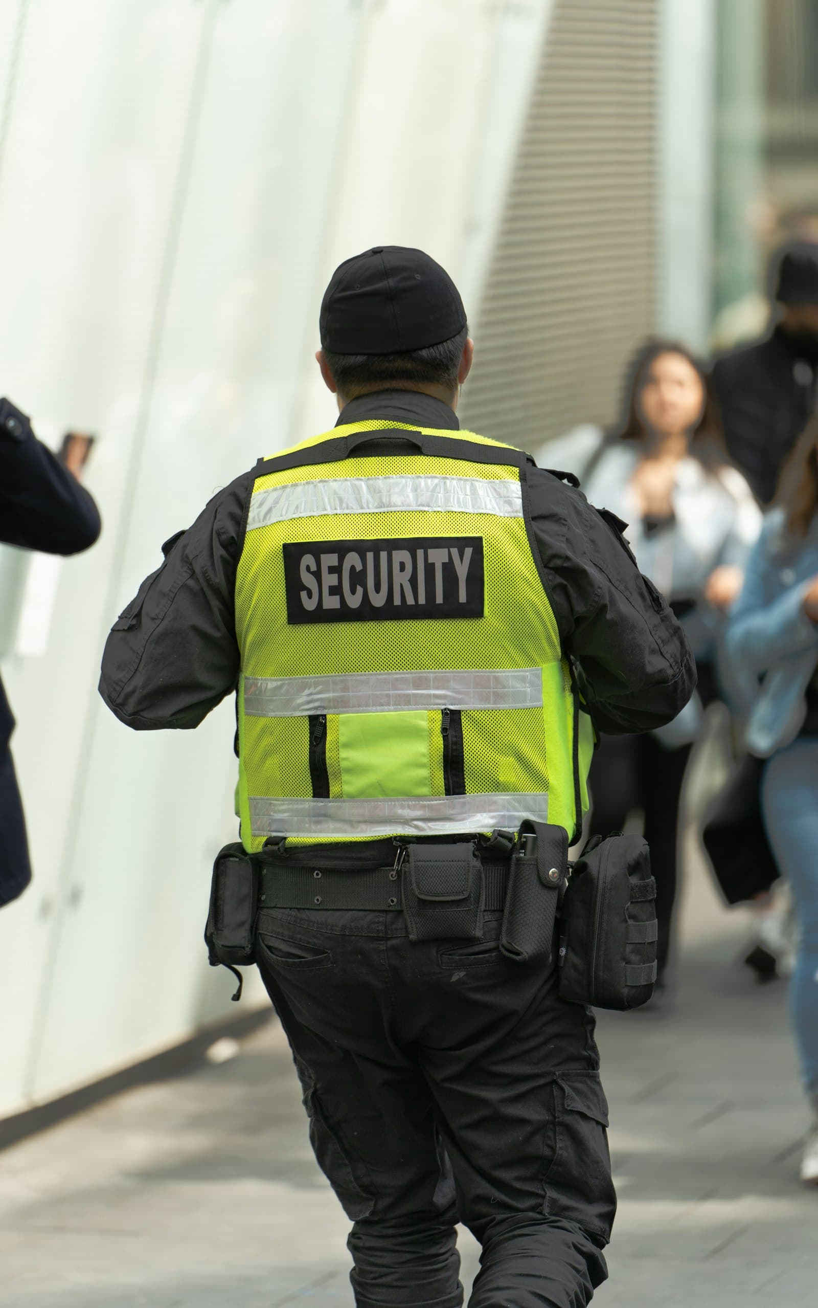 Sicherheitsmitarbeiter mit Security-Weste im Einsatz, von hinten